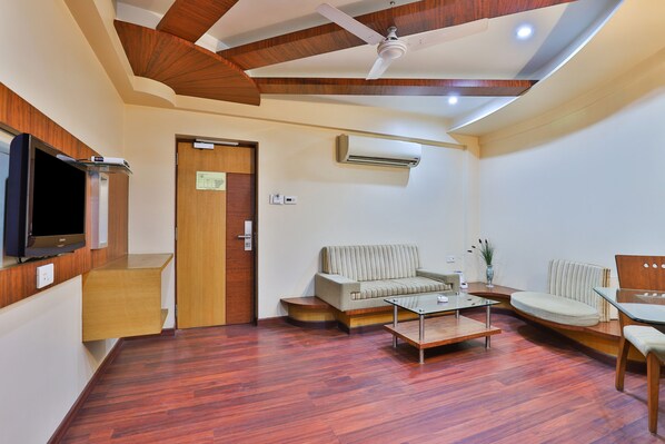 A modern living room with a sofa, armchairs, a coffee table, and a flat-screen TV. - Hotel President (Vadodara)