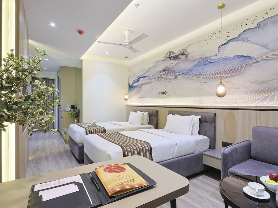 A hotel room with two beds, a seating area, a dining table, and a mural on the wall.
