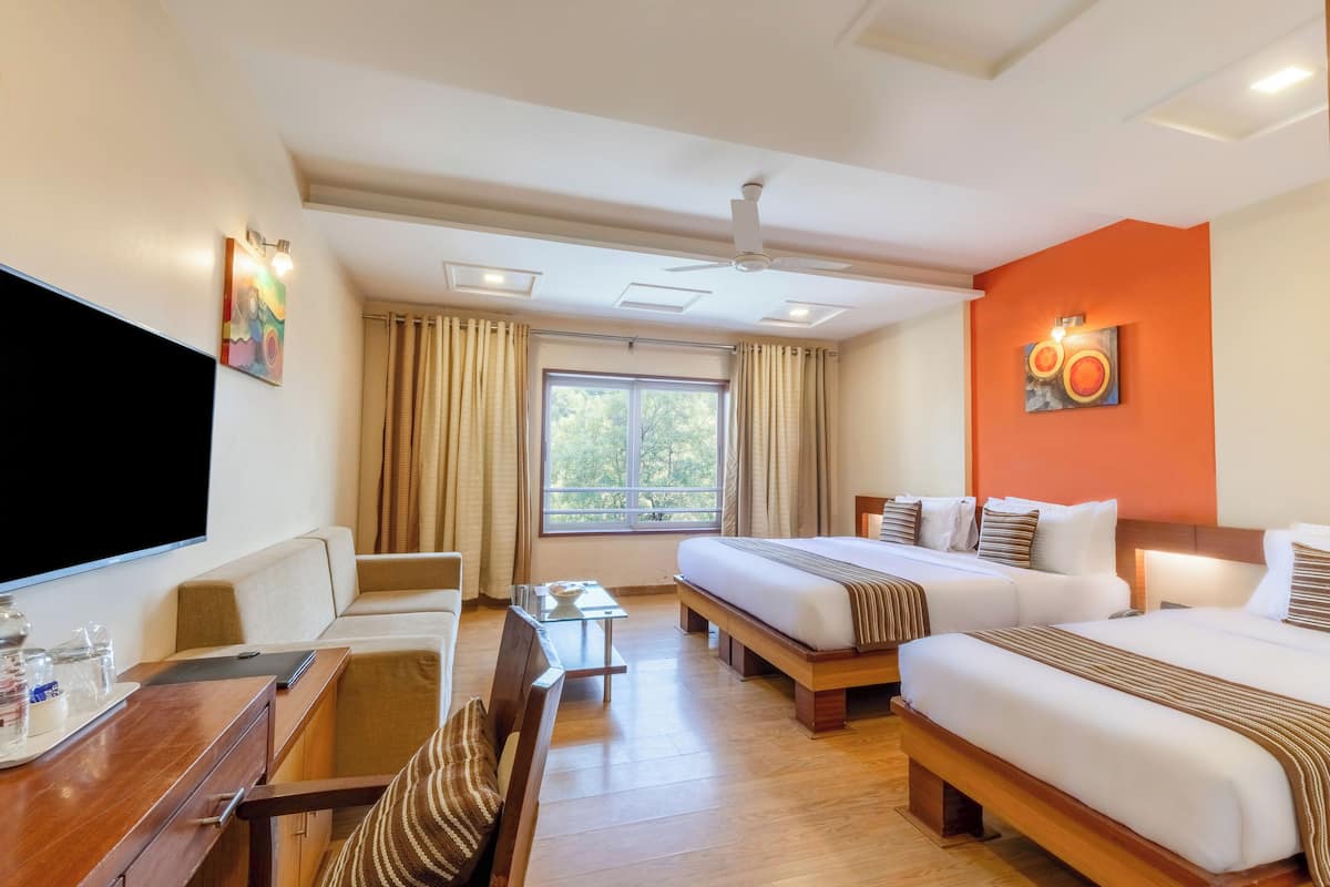 A hotel room with a large bed, a desk with a chair, a TV, and a window with curtains.
