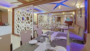 Un comedor con mesas dispuestas para el servicio, un separador decorativo blanco y un techo con diseño de estrellas.