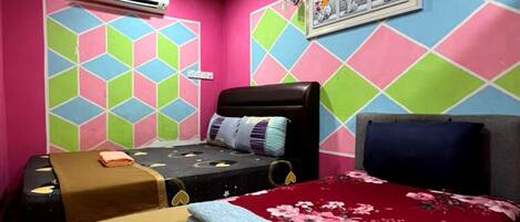 A room with two beds, colorful geometric wall patterns, an air conditioning unit, and a framed picture on the wall.