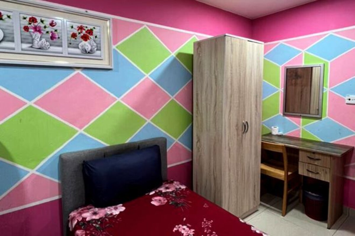 A bedroom with a bed, a wardrobe, a desk, and a mirror.