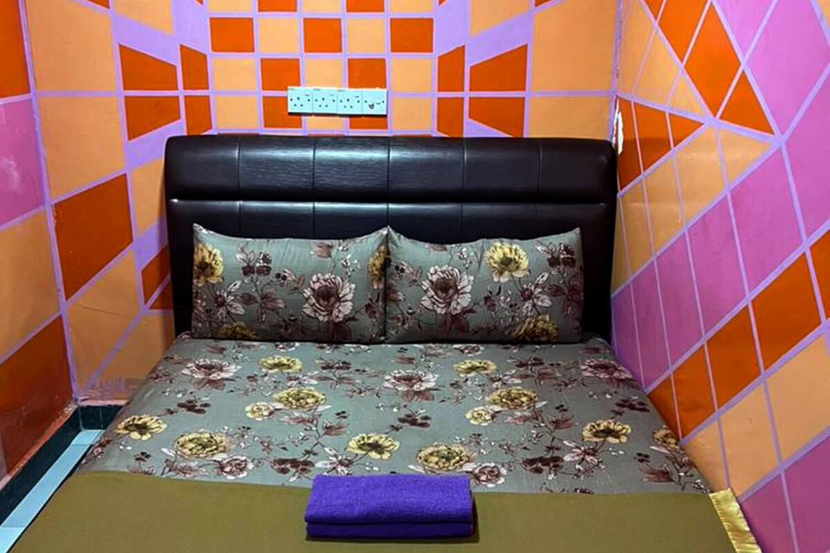 Een kleine, kleurrijke kamer met een bed, beddengoed met bloemmotieven en een hoofdbord.
