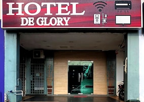 Entrada de un hotel con un letrero que dice "HOTEL DE GLORY", una cámara de seguridad y un símbolo de Wi-Fi.