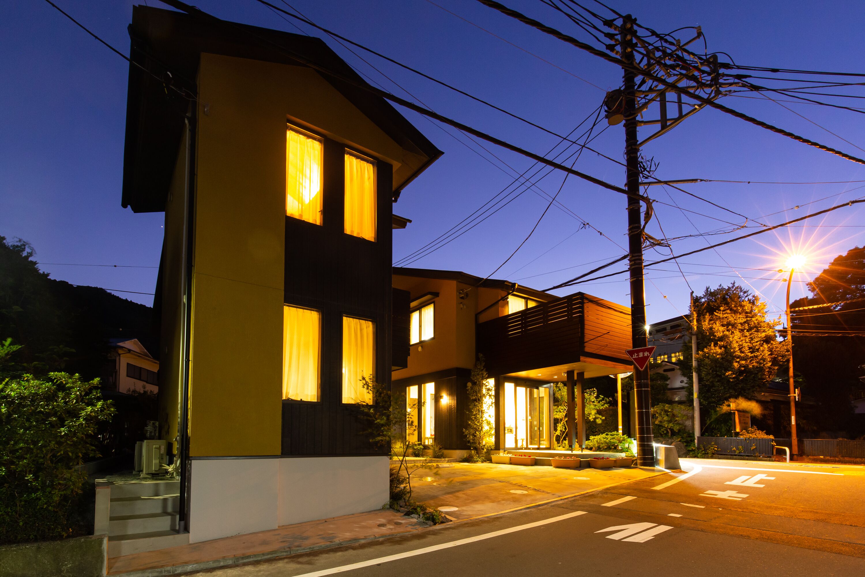 Uma casa moderna de dois andares, com entrada bem iluminada e área externa para sentar visível.