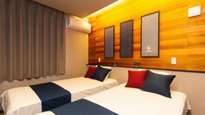 A hotel room with two beds, wooden paneling on the walls, an air conditioning unit, and a window with curtains.