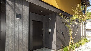 A modern building entrance with a dark door, security cameras, and a sign indicating the direction to the west wing.