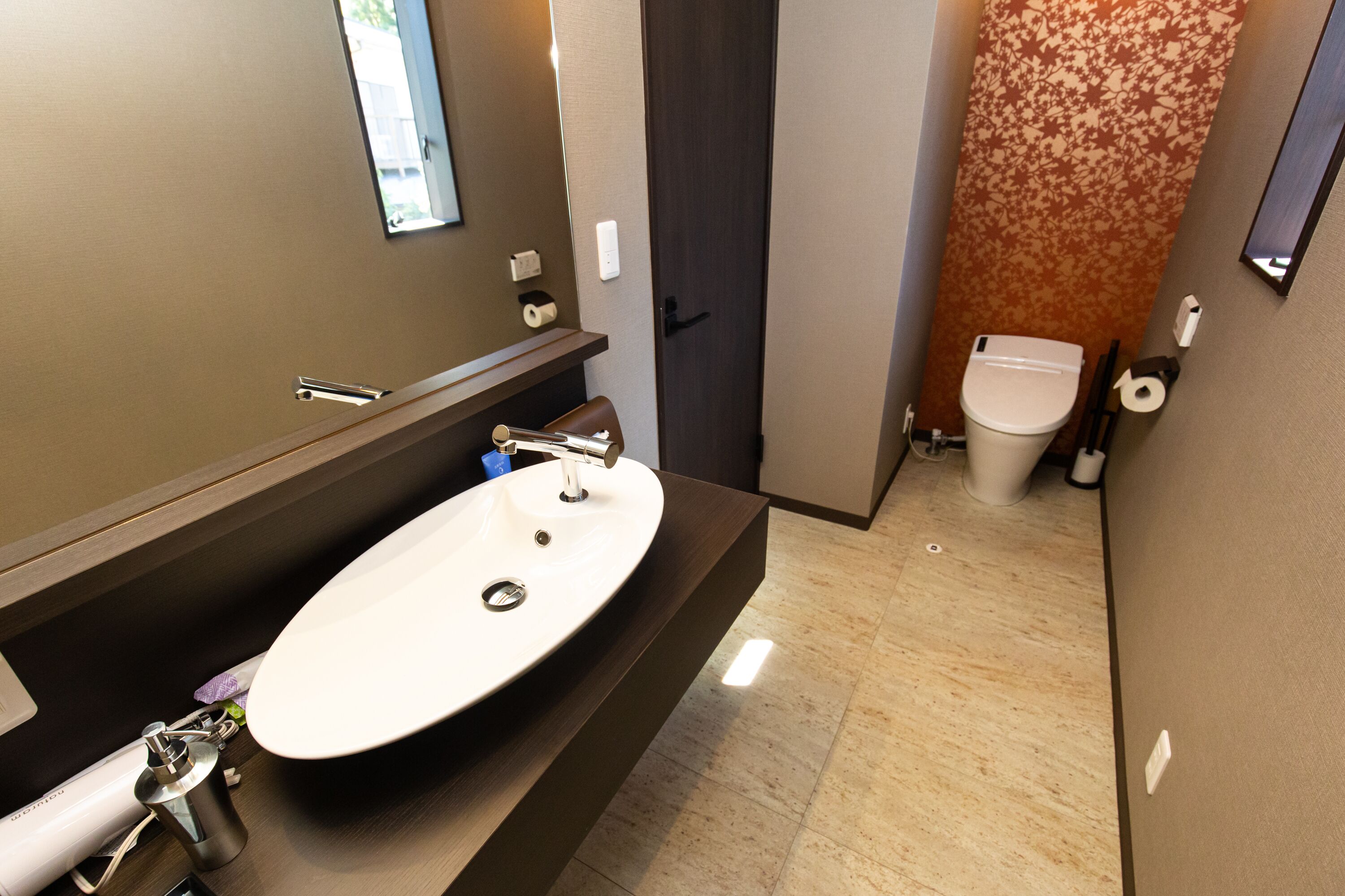 A modern bathroom with a large sink, mirror, and toilet.