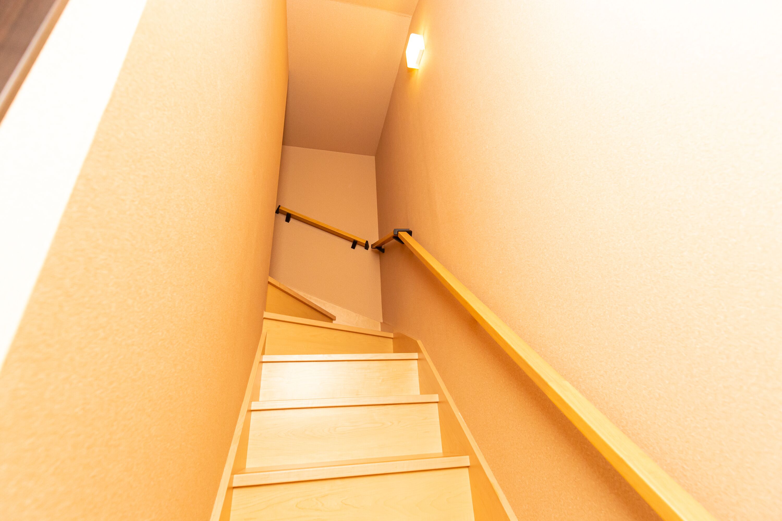 A staircase with wooden steps and a yellow handrail, leading upwards.