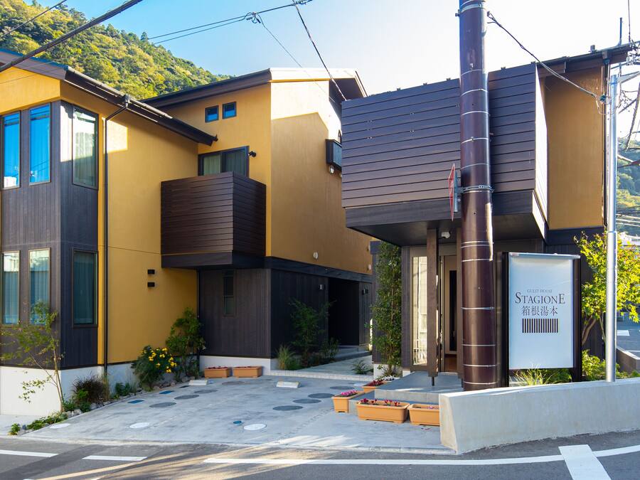 A modern building with a yellow facade, large windows, and a sign indicating it is a hotel.