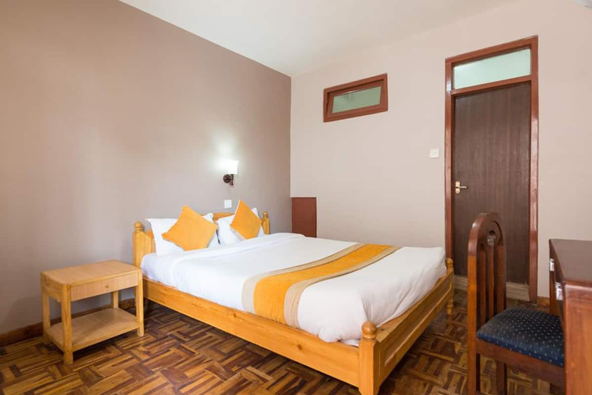 A bedroom with a wooden bed, a nightstand, a chair, and a door.