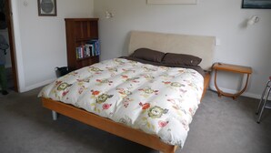A bedroom with a bed, a bookshelf, a small table, and two wall-mounted lamps. - ** Cake by the Ocean ** (St Clair)