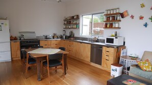 A kitchen with wooden cabinets, a dining table with chairs, a microwave, and a sink. - ** Cake by the Ocean ** (St Clair)