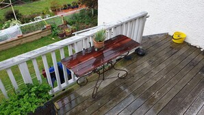 A wooden deck with a table and chairs, surrounded by a white railing. - ** Cake by the Ocean ** (St Clair)