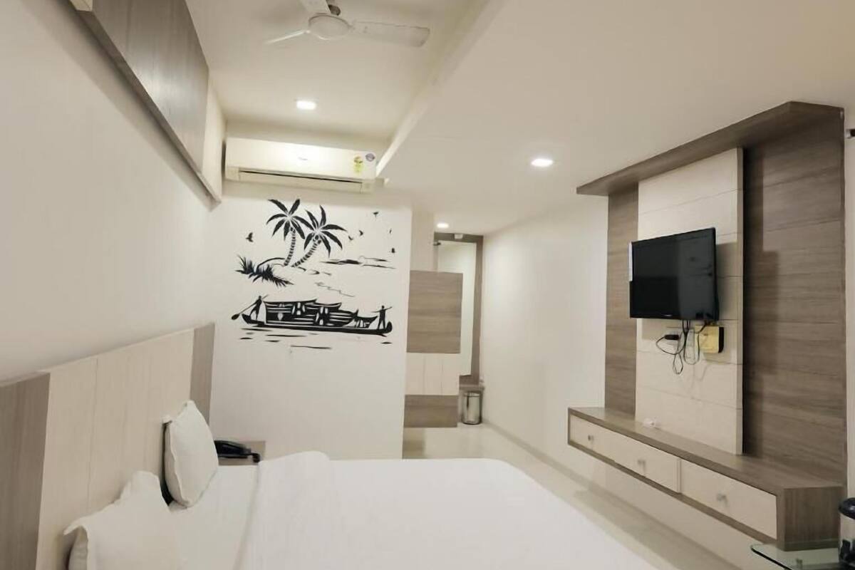 Um quarto moderno com uma cama, uma TV fixada na parede e um ventilador de teto.