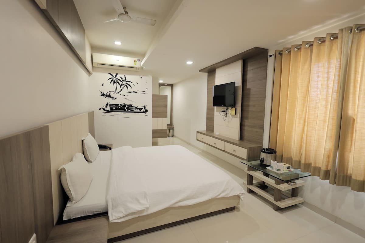 Quarto moderno com cama, televisão na parede, mesa de cabeceira e janela com cortinas.