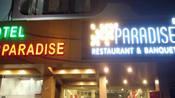 A building with a sign for 'Paradise Restaurant & Banquet' and a 'Paradise Hotel' sign. - Hotel Grand Paradise (Vadodara)