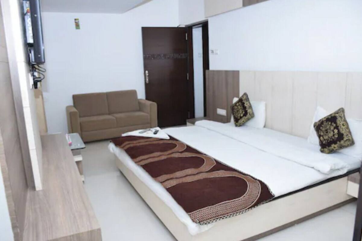 Quarto de hotel com cama, sofá, escrivaninha e porta.