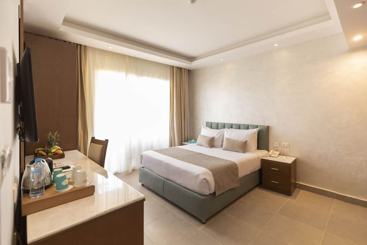 Une chambre d’hôtel comprenant un lit, une table de chevet et un bureau avec une chaise.