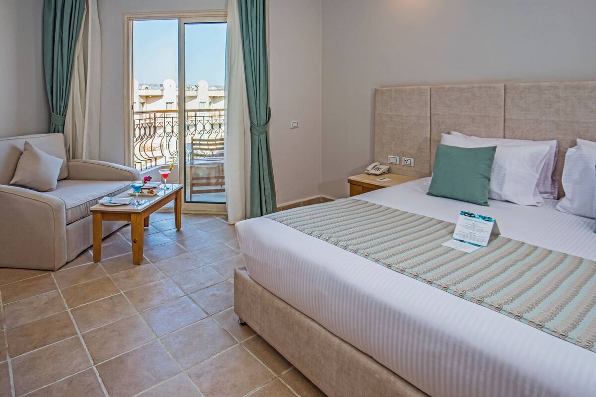 Une chambre d’hôtel avec un lit, un canapé, une petite table et un balcon doté d’une balustrade.