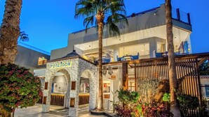 A modern hotel with a stone archway entrance, a rooftop terrace, and a well-lit lobby area.