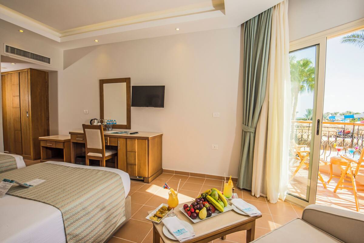 Une chambre d’hôtel comprenant un lit, un bureau et un balcon aménagé avec du mobilier d’extérieur.