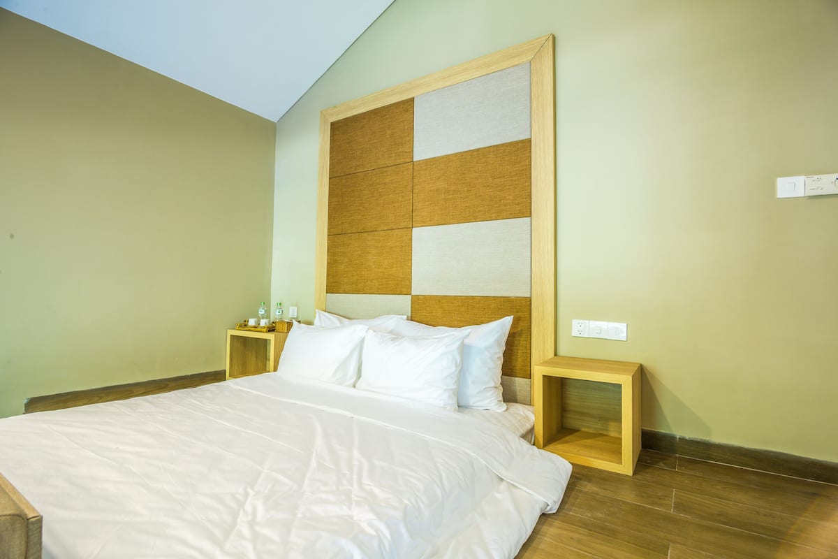 A neatly made bed with white linens in a room with a wooden headboard and nightstands.
