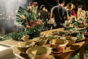A dining table with various dishes and a floral centerpiece. - Ba Ho Eco Beat (Nam Ninh Hoa)