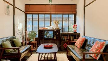 A traditional Japanese-style room with tatami mats, a low table, and a television.