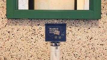 Un baño con pared de azulejos veteados, espejo con marco verde y lavabo blanco con sistema de filtración de agua MiniBleQ.