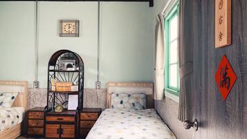 A bedroom with two beds, a radio on a shelf, a clock on the wall, and a wooden door with Chinese characters.