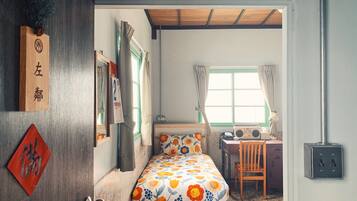 Une pièce comprenant un lit, un bureau et une chaise. Il y a une fenêtre avec des rideaux, une porte avec une poignée et un mur avec un interrupteur.