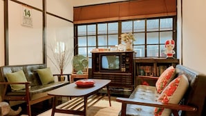 Een woonkamer met een bank, een salontafel, een televisie en een boekenkast.