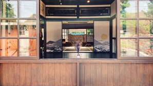 Een traditioneel Japans interieur met tatami vloeren, een laag houten plafond en uitzicht op een berglandschap door grote ramen.