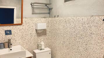 A compact bathroom with a toilet, sink, and shower.