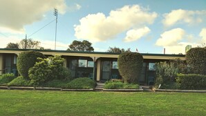 A two-story building with a green roof, a flag, and a sign indicating a 'New Pine Hotel'. - Pinehaven Motel (Nelson)