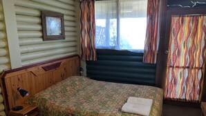A room with a wooden bed, a desk, a chair, and a window with curtains. - Pinehaven Motel (Nelson)