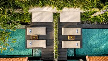 A poolside area with two seating areas, each with a small table and a bench.