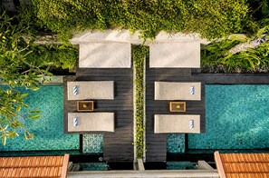 A poolside area with two seating areas, each with a small table and a bench. - Del Cielo Villa Seminyak (Keroboken Kelod)