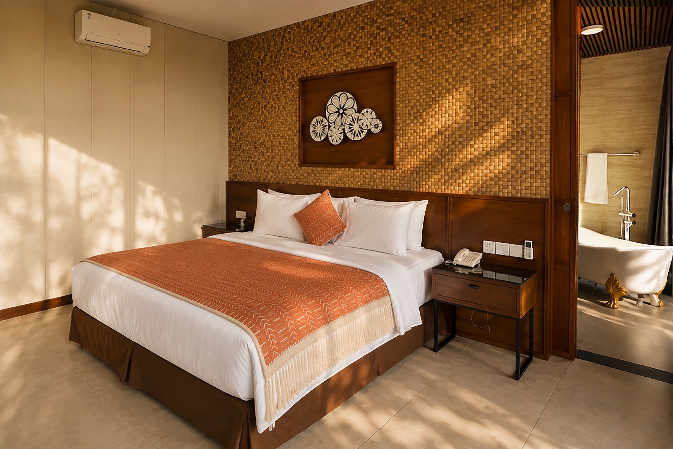 A hotel room with a large bed, a bedside table with a phone, a wall-mounted artwork, and a bathroom with a bathtub and sink.
