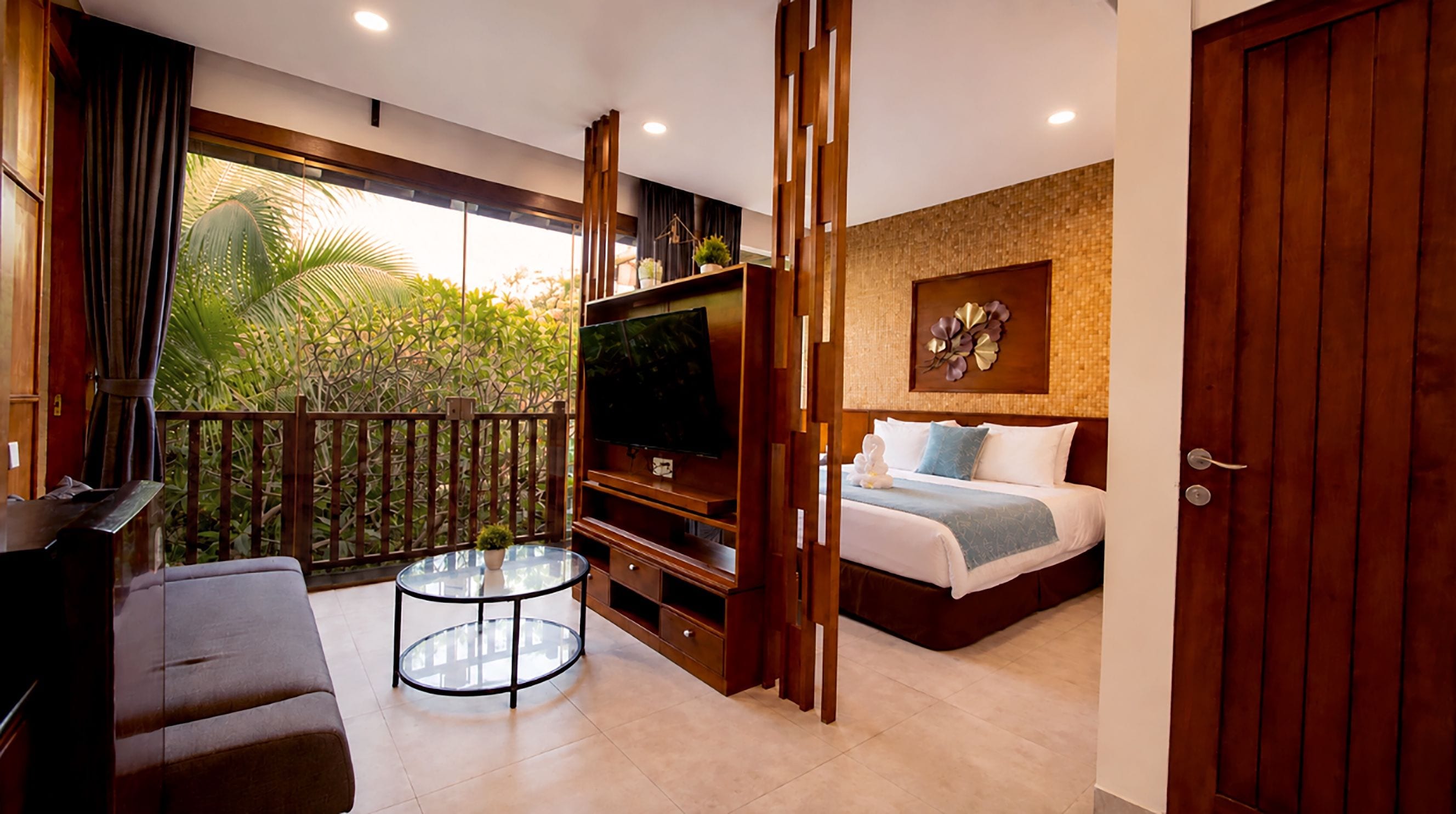 A modern hotel room with a balcony, a TV, a bed, and a round table.
