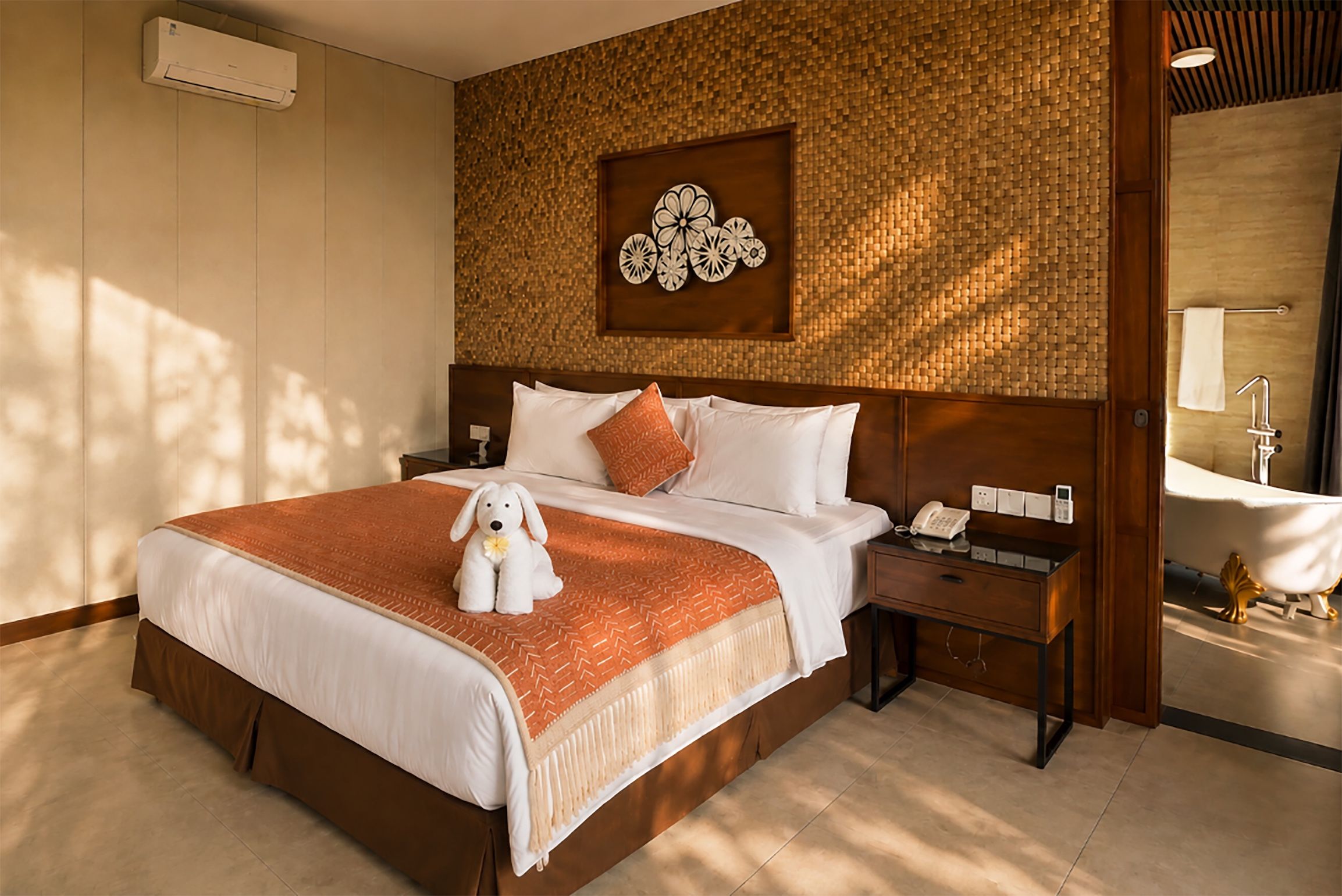 A hotel room with a large bed, a nightstand, a wall-mounted telephone, and a bathroom with a bathtub.