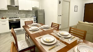 A modern kitchen with white cabinets, a stainless steel range hood, and a built-in oven. - Villa Elisa Apartments (Minturno)