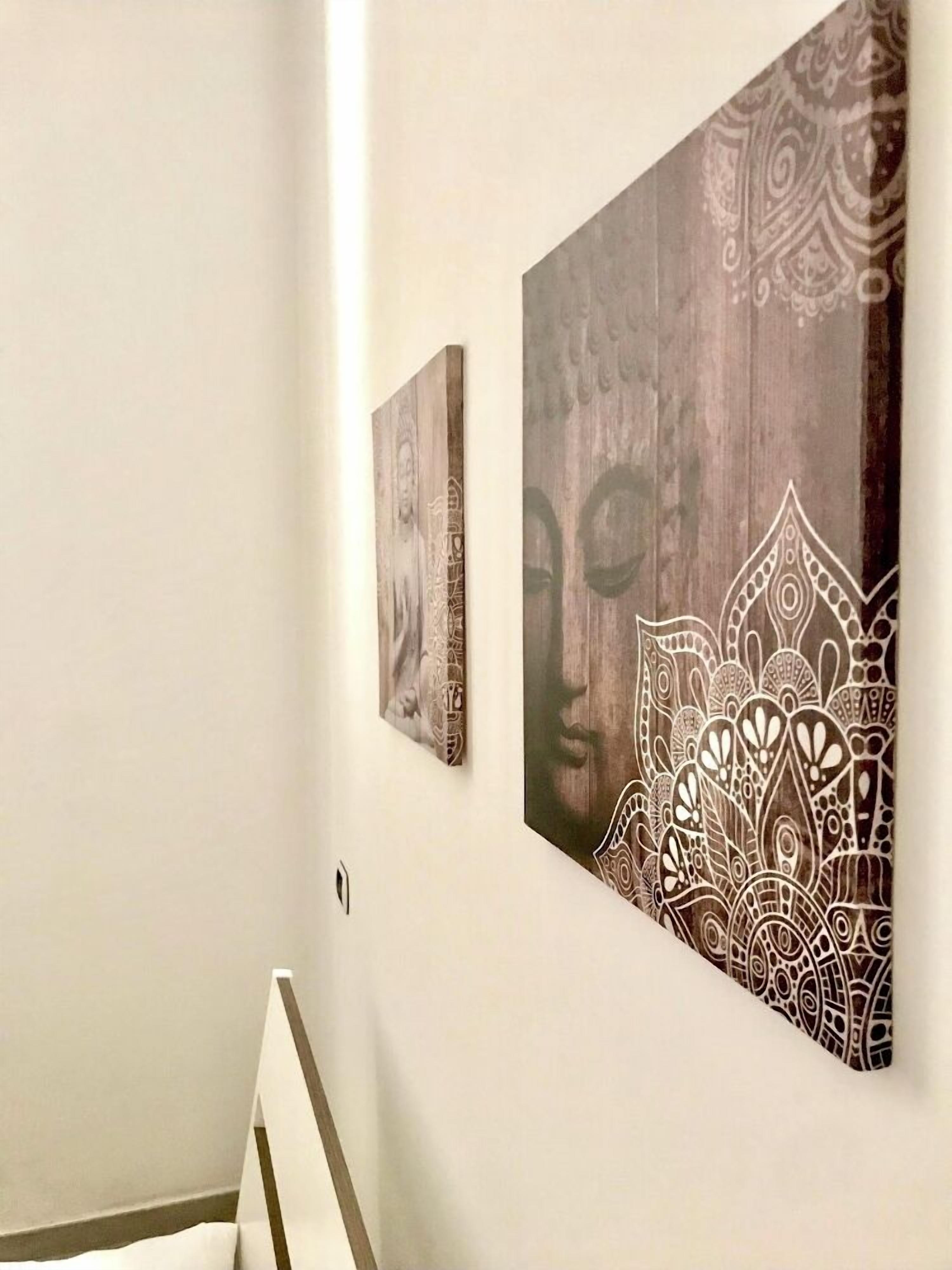 A hallway with two wall-mounted artworks, one depicting a face and the other a mandala pattern.