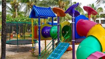 Un parque infantil con tobogán, estructuras para escalar y un trampolín.