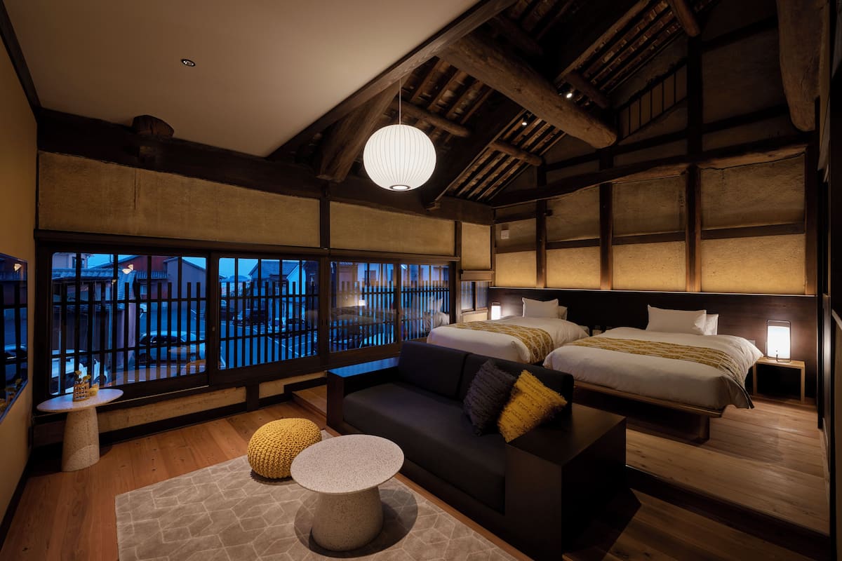 A traditional Japanese-style bedroom with a low ceiling, wooden beams, tatami flooring, and sliding shoji doors.