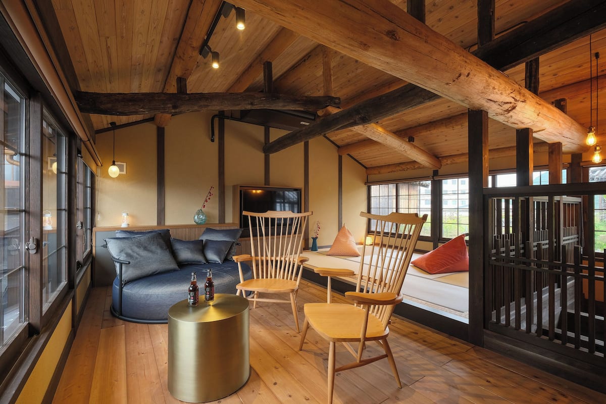 A wooden interior with a sofa, chairs, and a round table.