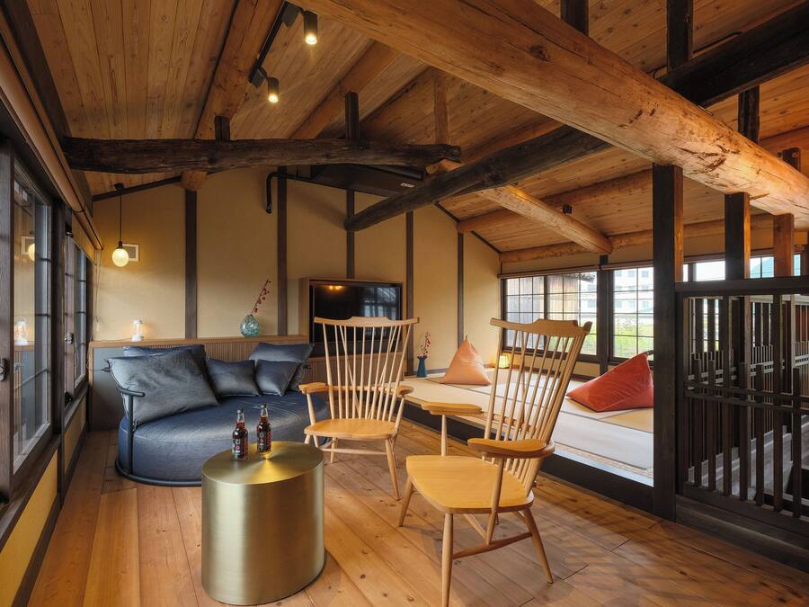 A wooden interior with a sofa, chairs, and a round table.