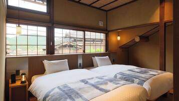 A hotel room with two beds, a view of a traditional building, and a wooden ceiling.