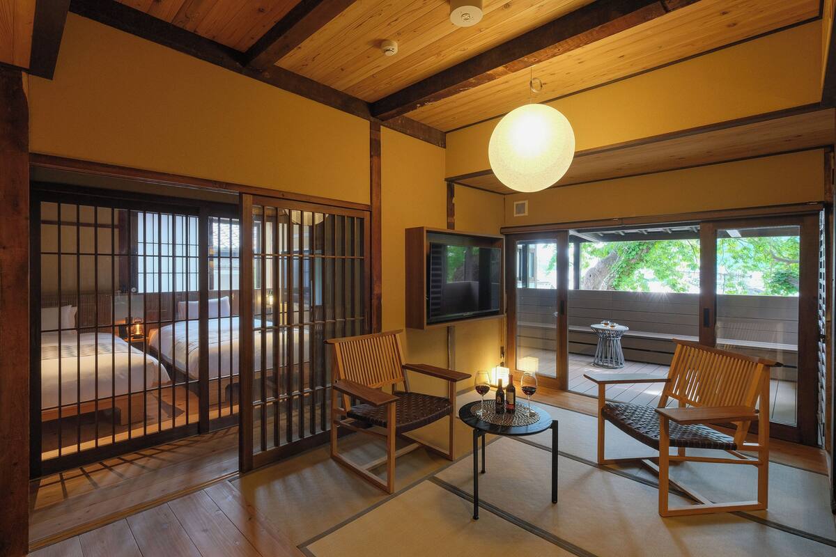 A traditional Japanese room with tatami flooring, sliding doors, and a television.